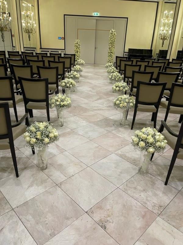 Eine Stuhlreihe mit Blumenvasen auf dem Boden