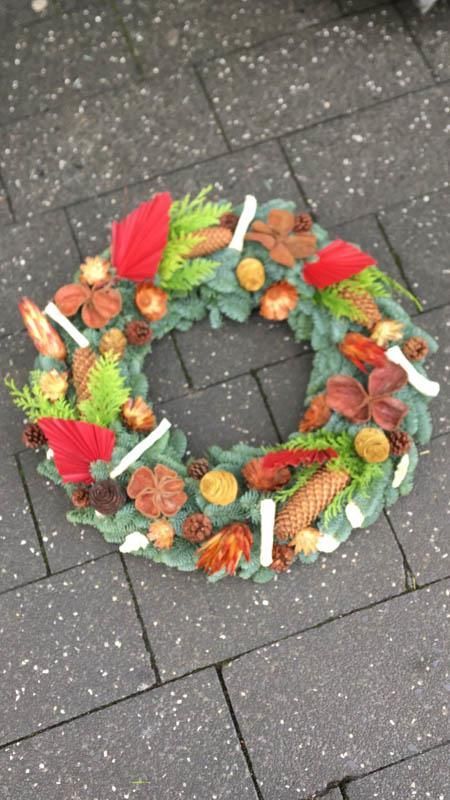 Auf einem gepflasterten Gehweg liegt ein Weihnachtskranz.