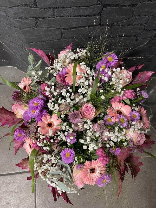 Ein Strauß rosa und violetter Blumen steht auf einem gefliesten Boden.