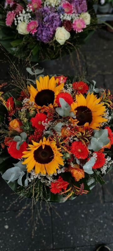 Auf dem Boden liegt ein Strauß Sonnenblumen und anderer Blumen.