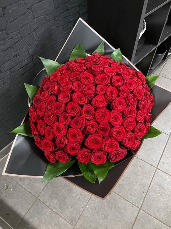 Ein großer Strauß roter Rosen in schwarzes Papier eingewickelt