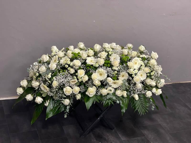 Ein Strauß weißer Blumen steht auf einem Tisch.