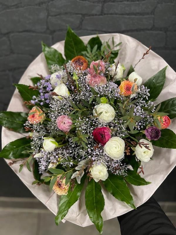 Eine Person hält einen in Papier eingewickelten Blumenstrauß.