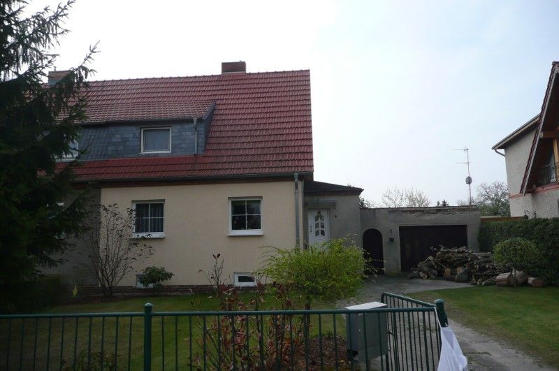 Sanierung Einfamilienhaus mit gelblicher Fassade und rotem Dach.