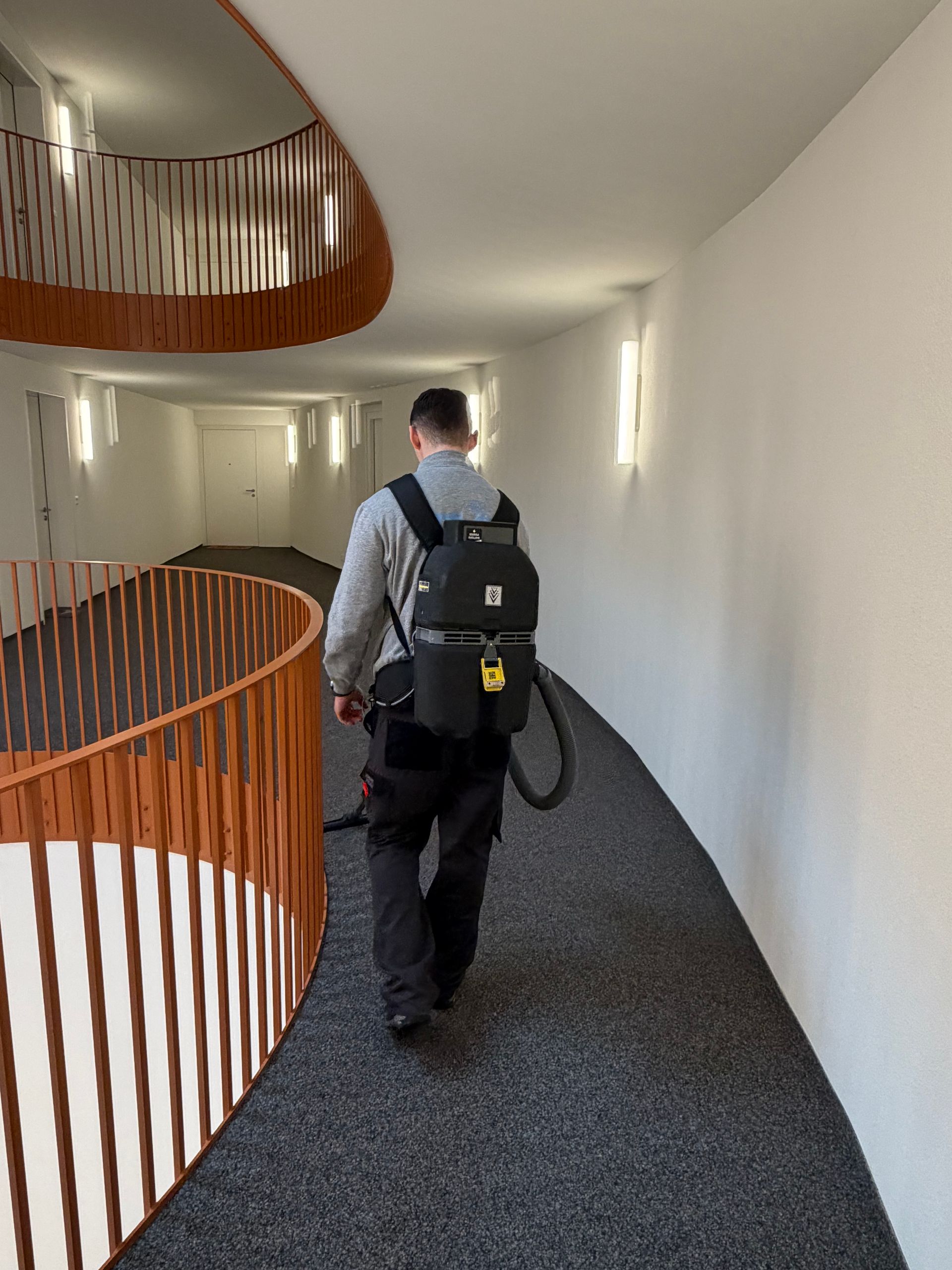 Eine Person reinigt mit einem flachen Mopp eine dunkle, gemusterte Marmortreppe.