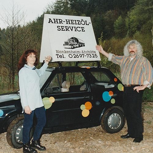 Ein Mann und eine Frau halten ein Schild mit der Aufschrift „Ahr-Heizöl-Service“