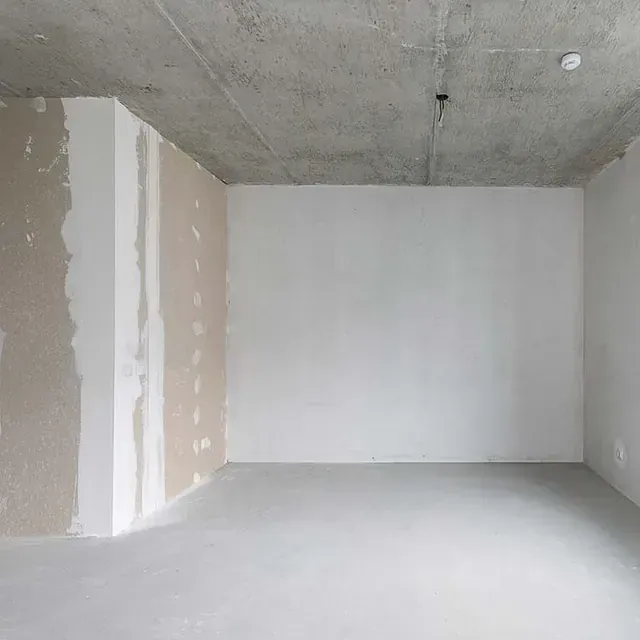 Una habitación vacía con paredes blancas y un techo de hormigón.