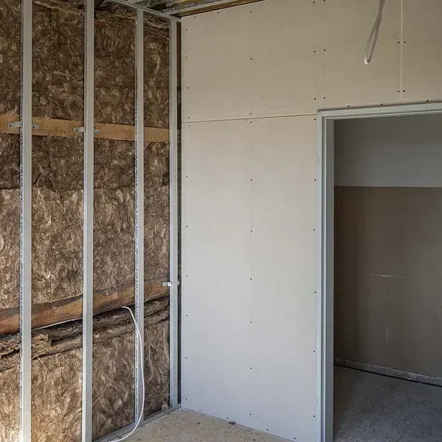 Una habitación con una puerta y una pared con aislamiento.