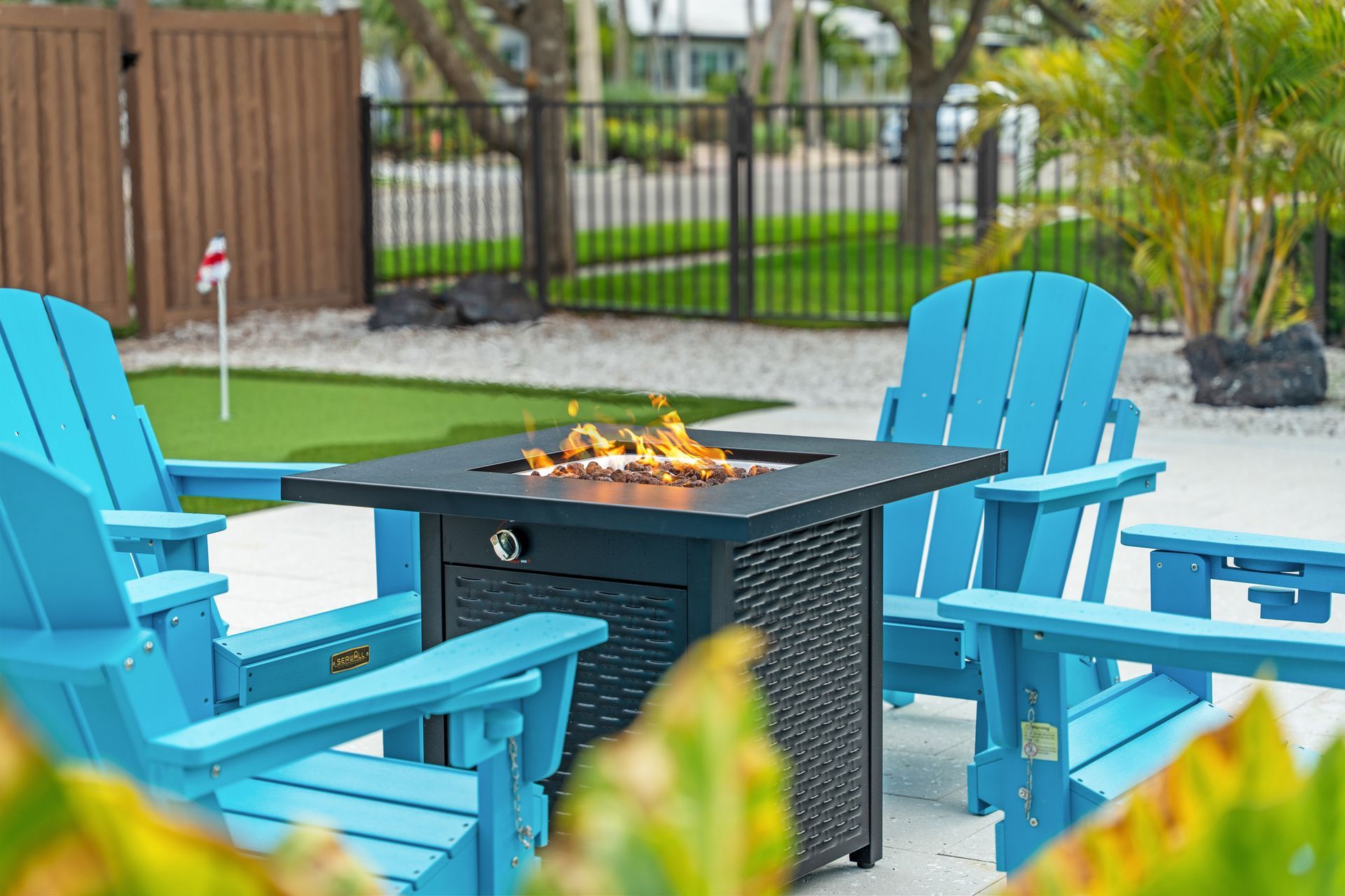 Blue patio chairs around a fire pit in a backyard patio setting