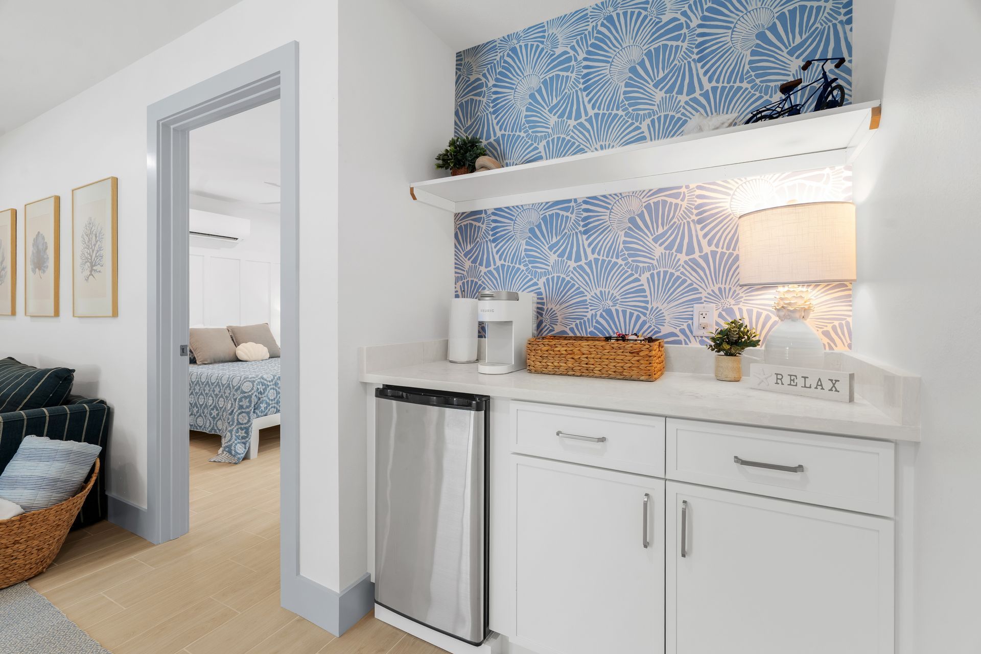 Bright white hallway with built-in cabinet, shelf, lamp, and blue floral wallpaper accents