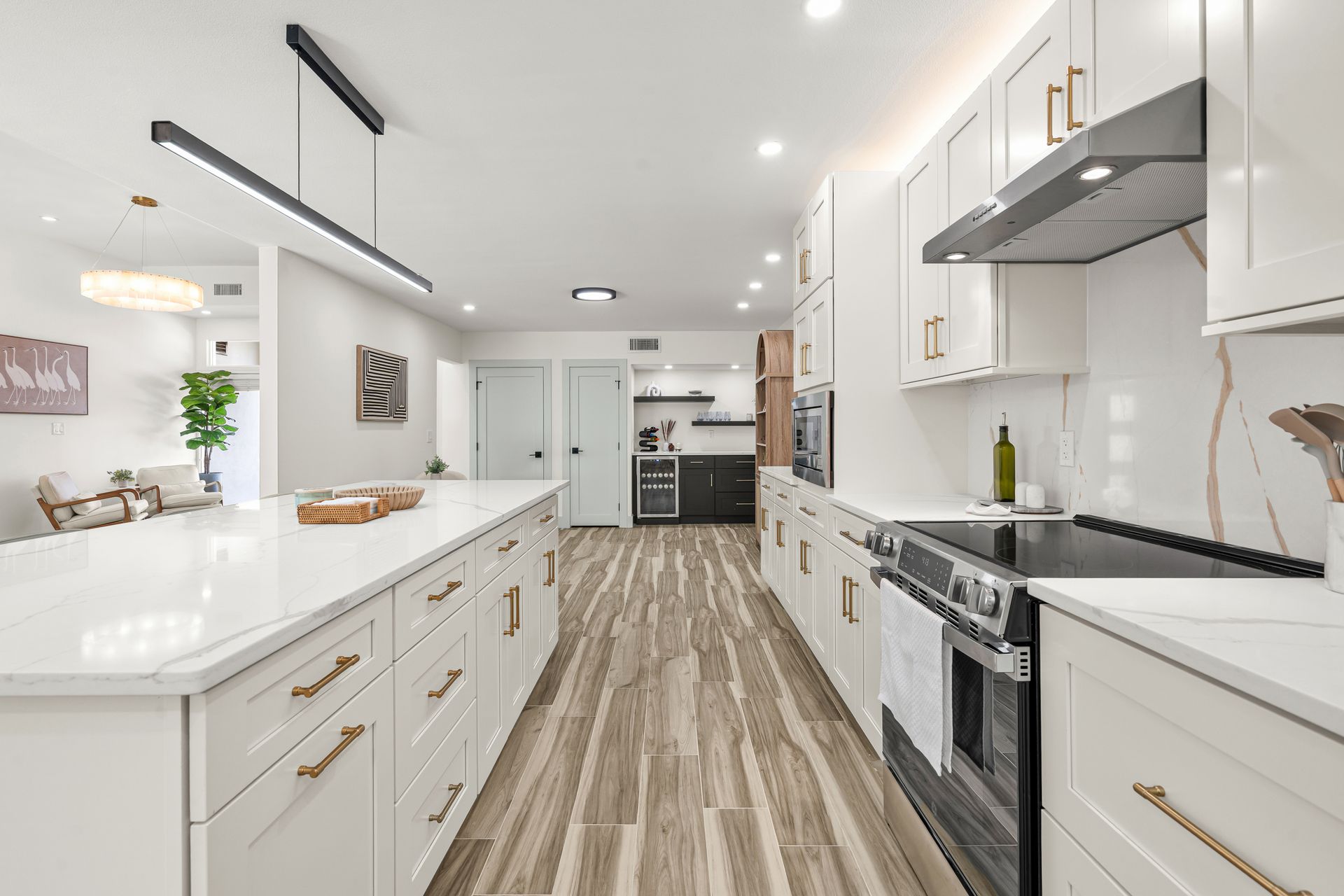 Bright modern white kitchen with island, stainless appliances, and wood-look floor