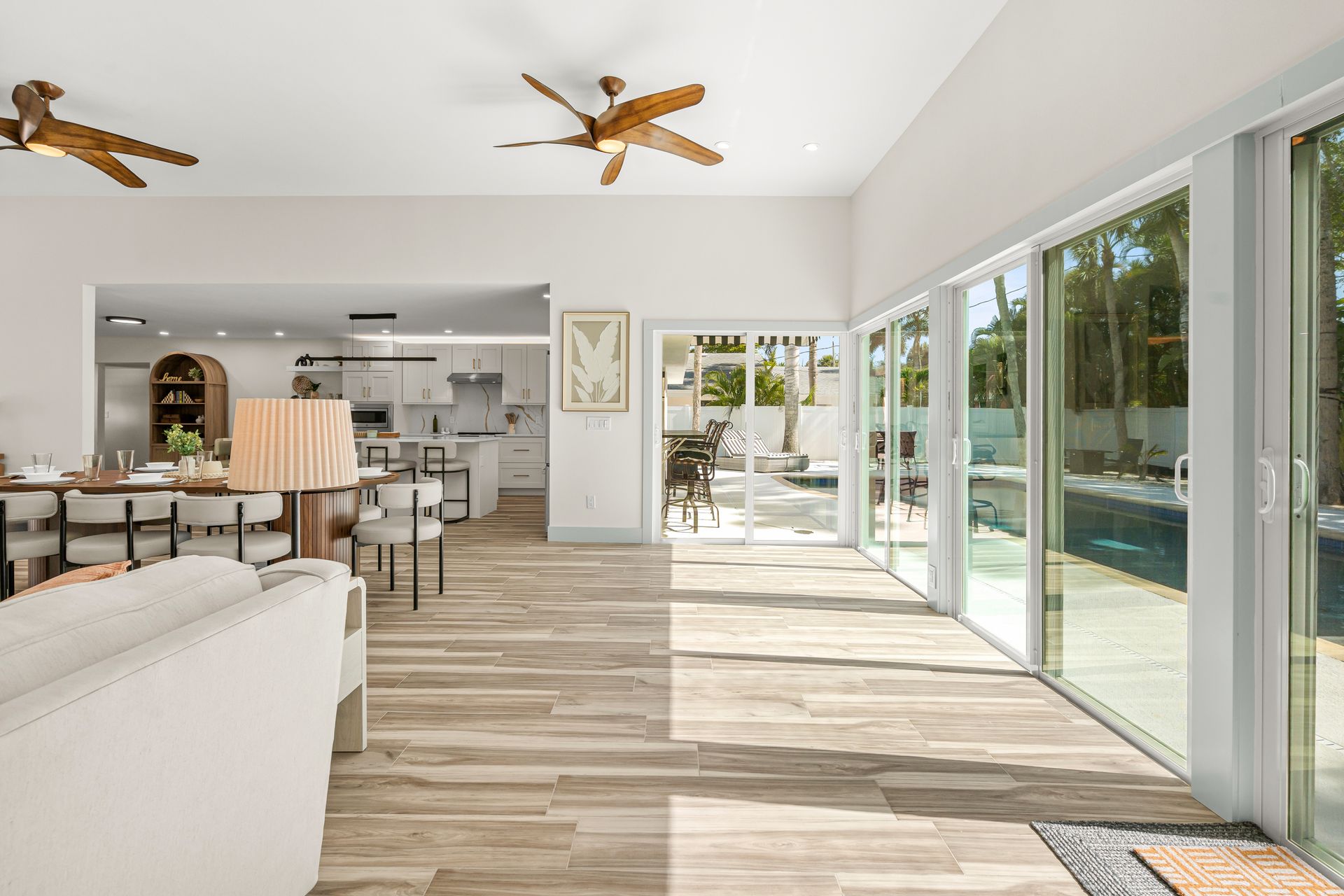 Bright airy living room with white furniture, ceiling fans, and sliding glass doors to a patio.