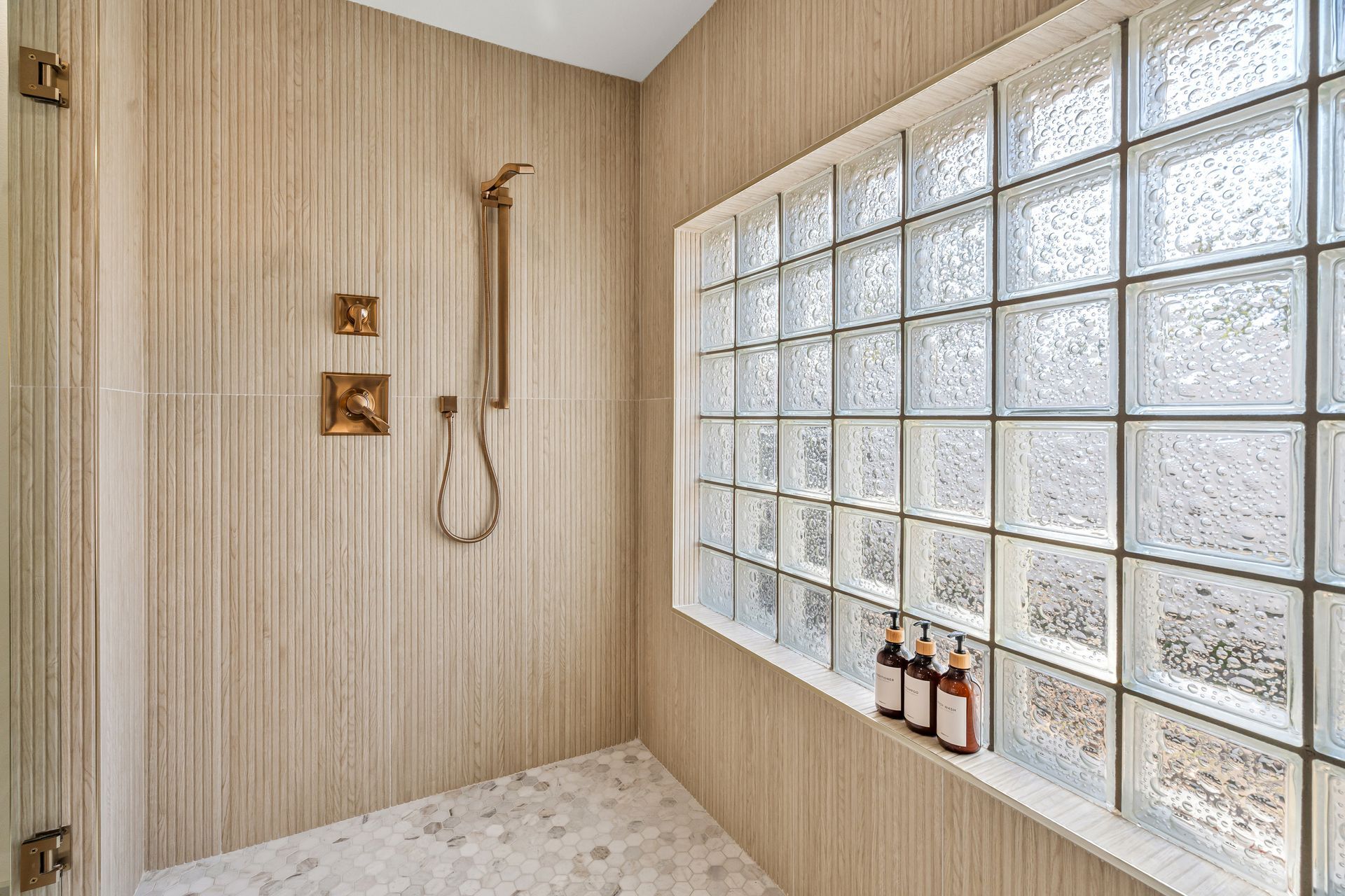 Modern shower with glass block wall, rainfall showerhead, and beige tile walls in a bright bathroom