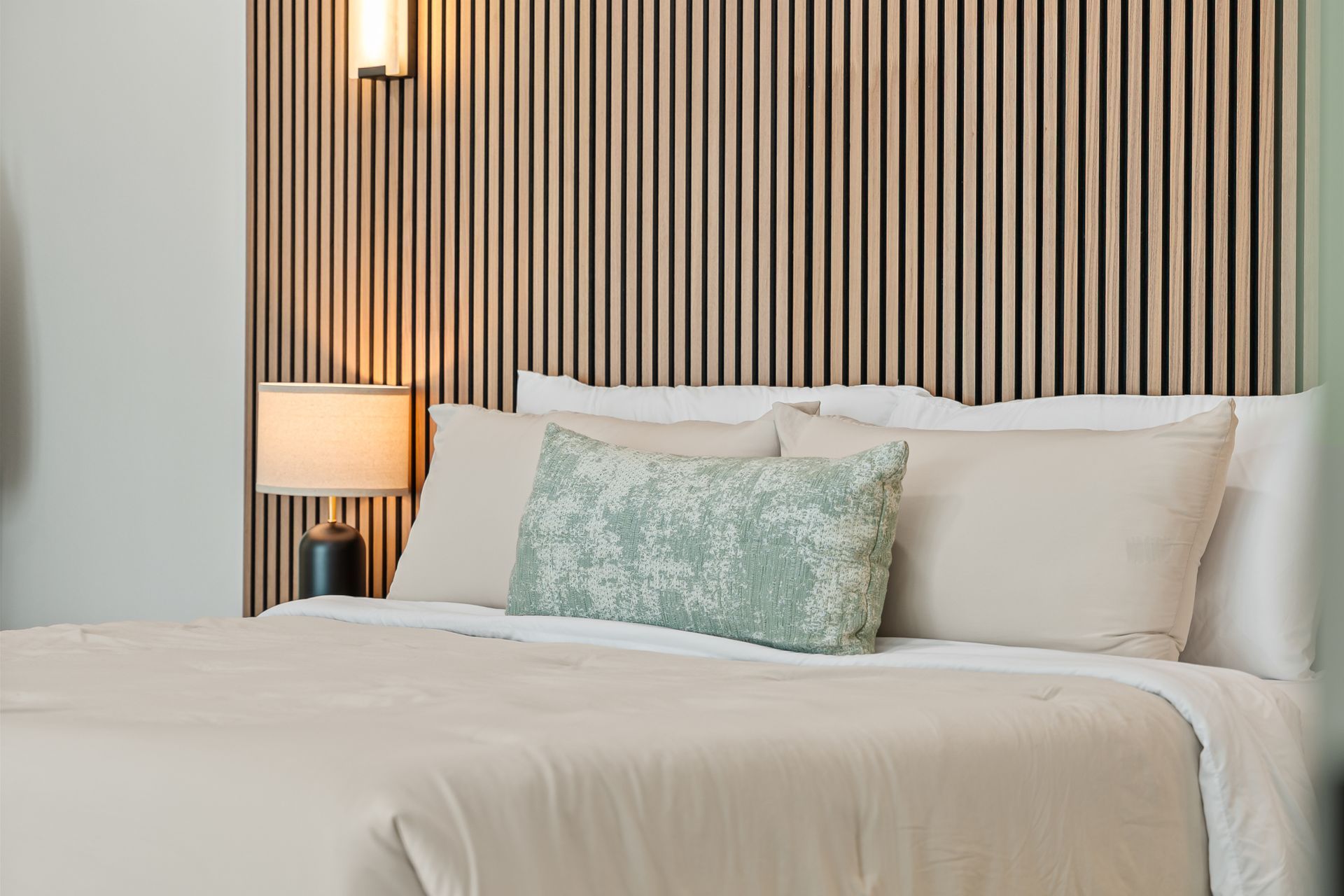 Modern bedroom with a striped wood headboard, white bedding, and a bedside lamp