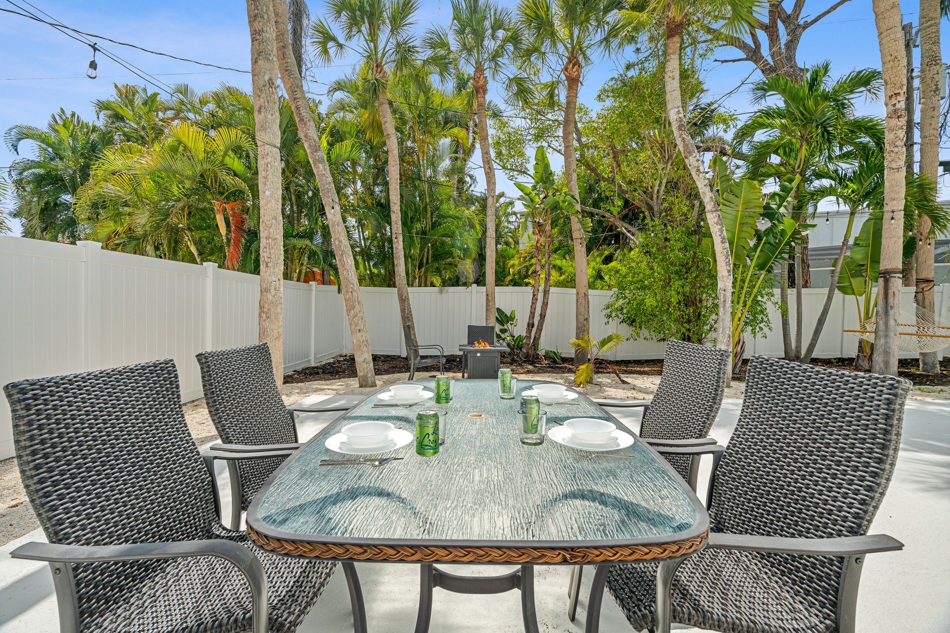 Outdoor patio with glass table and woven chairs in a tropical backyard