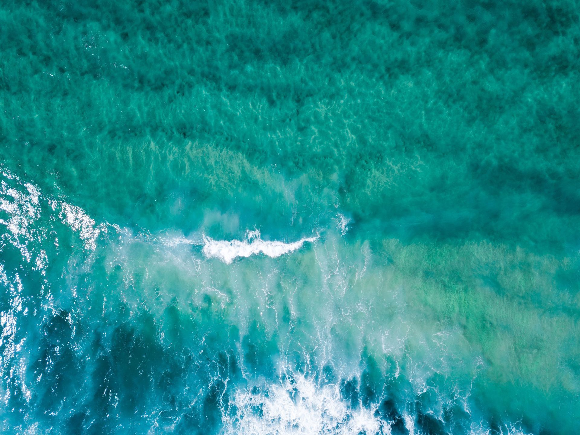 Turquoise ocean waves breaking in white foam near the shore