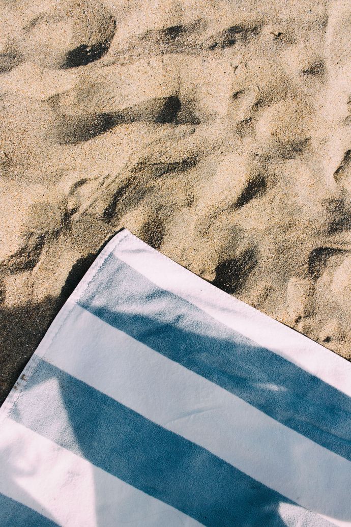 Striped blue-and-white towel on sandy beach