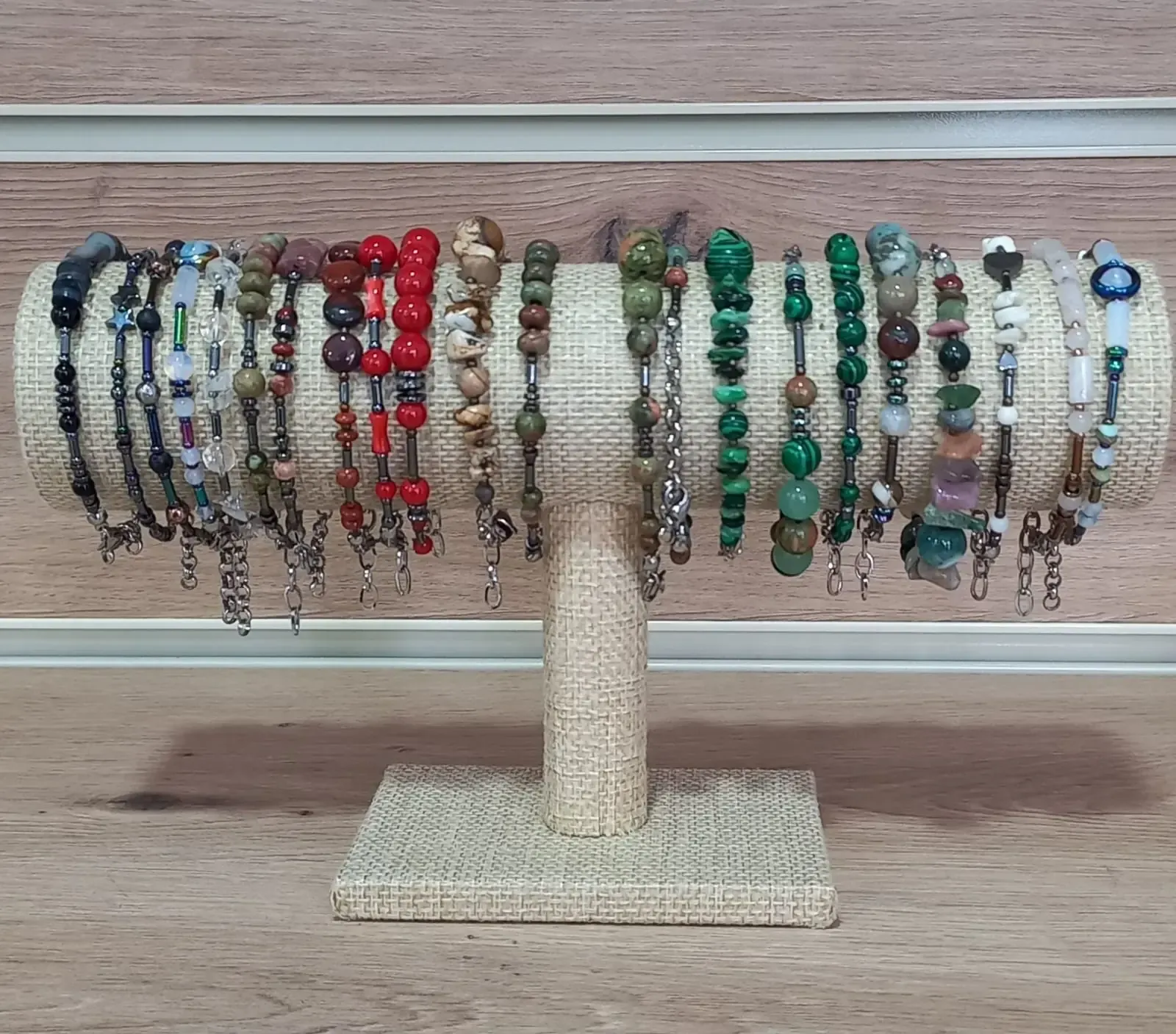 Un expositor sostiene una fila de pulseras de cuentas con varios colores y texturas.