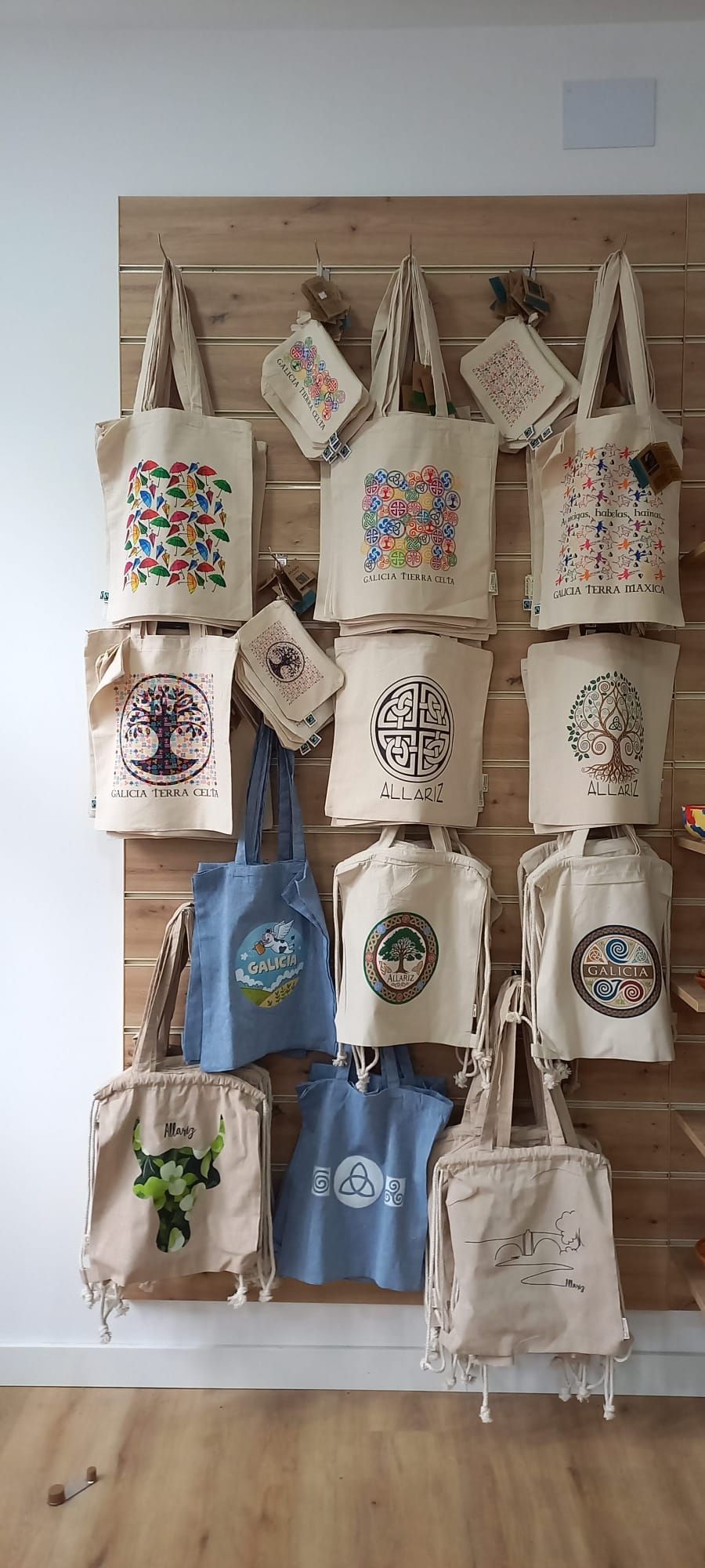 Exhibición de varias bolsas de mano con diferentes diseños en una pared de madera.