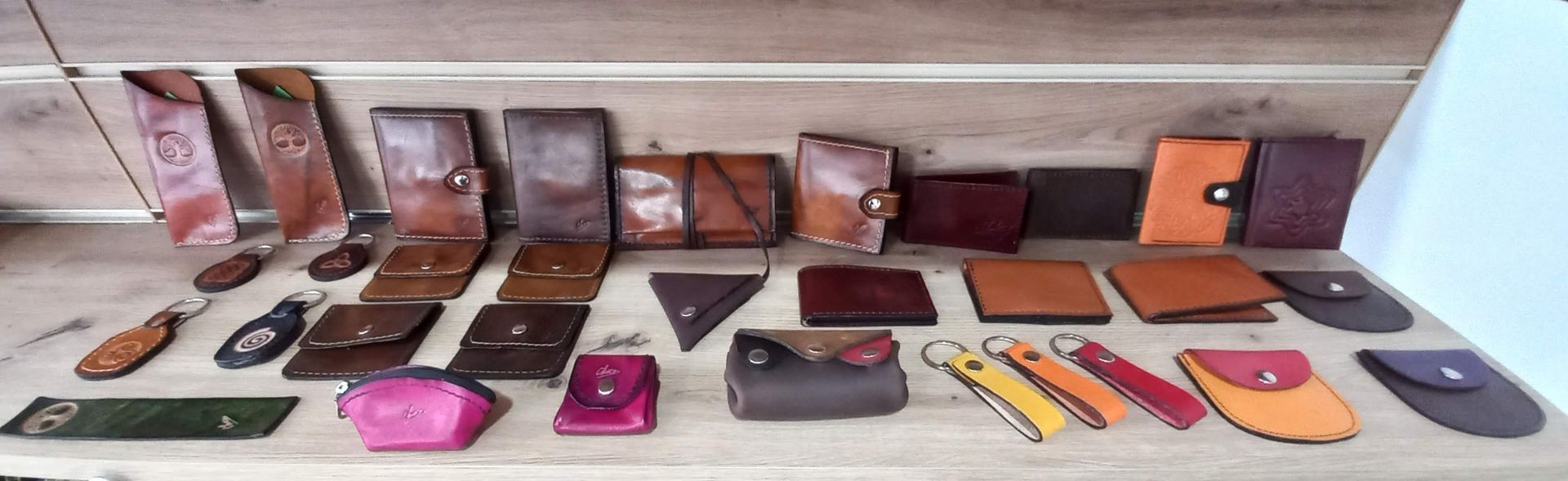 Surtido de carteras y llaveros de cuero hechos a mano expuestos en un estante de madera.