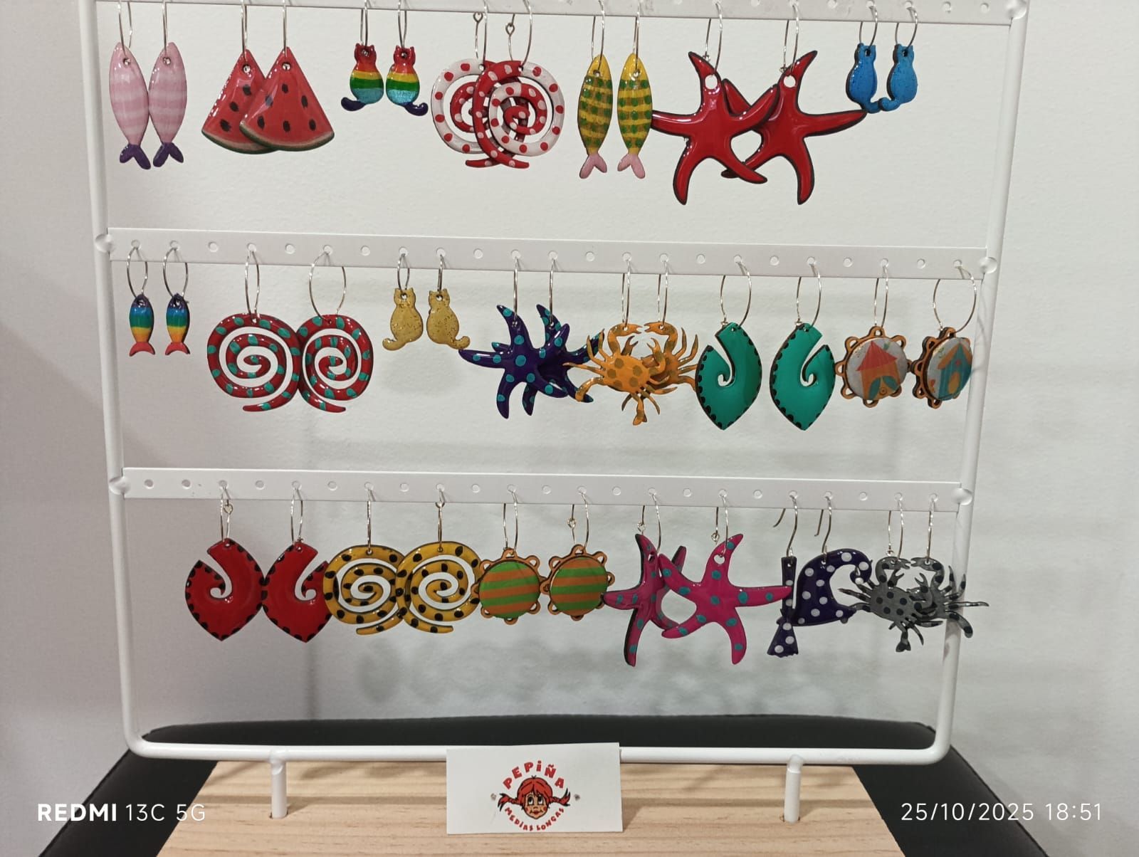 Exhibidor de aretes con diseños coloridos de temática marina: peces, estrellas de mar y formas espirales.