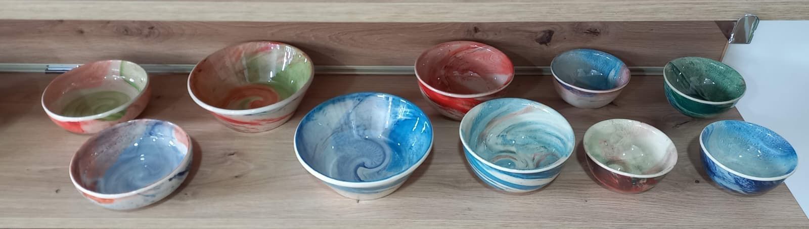 Once cuencos de cerámica de colores sobre un estante de madera.