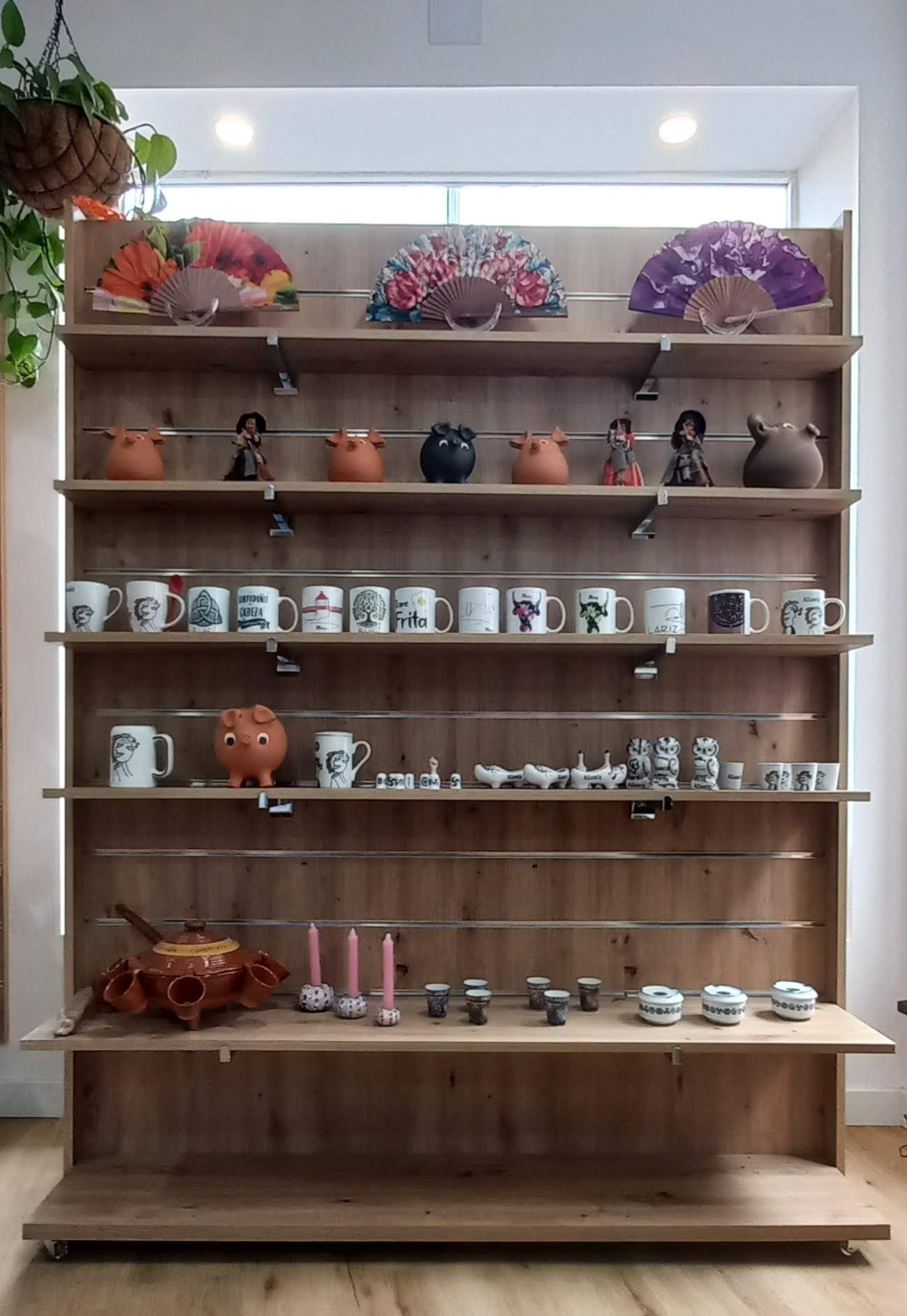 Los estantes de madera exhiben diversos artículos de cerámica: tazas, figuras, cuencos y piezas decorativas.