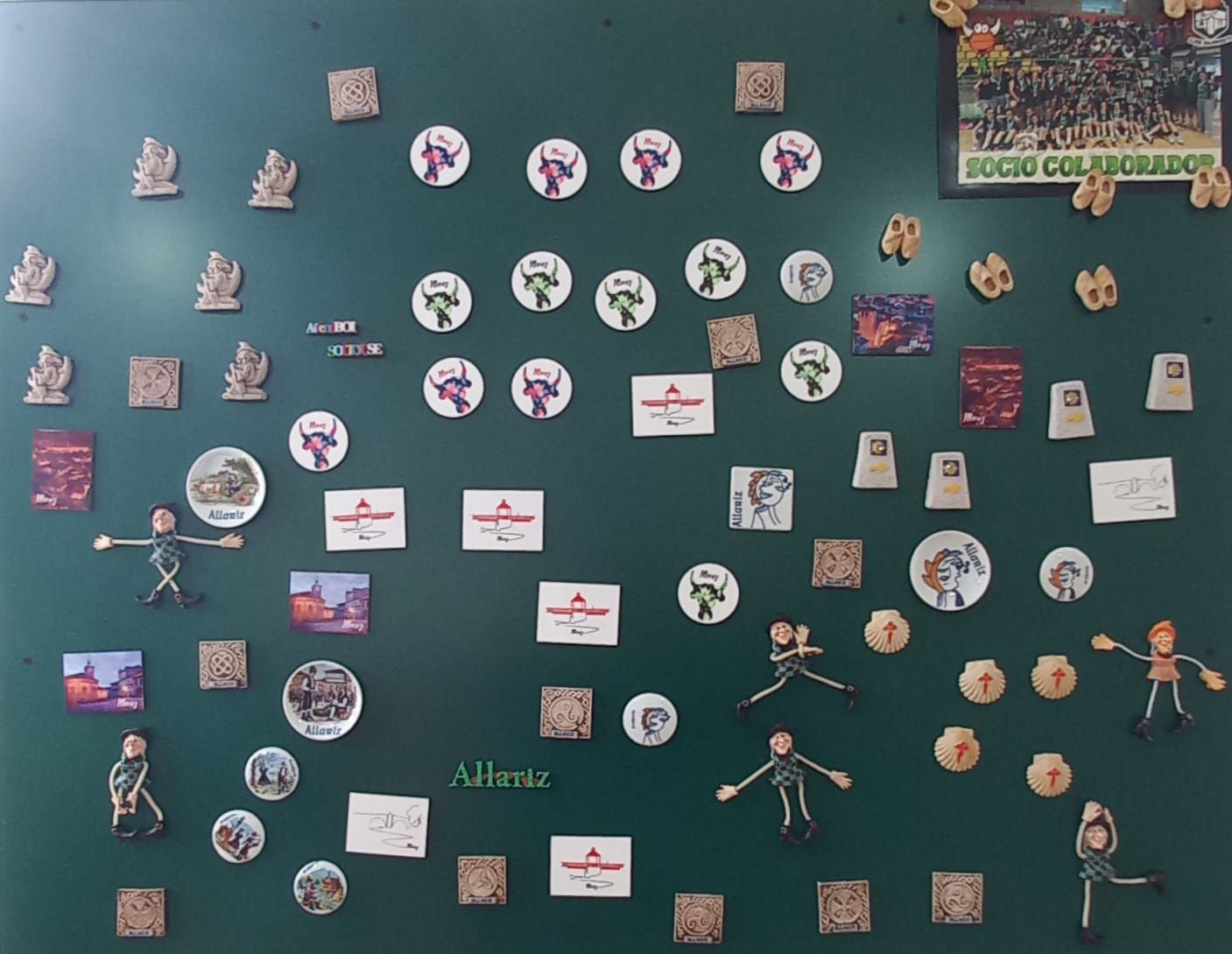 Tablón de anuncios verde cubierto de imanes: círculos, cuadrados, figuras y monigotes.