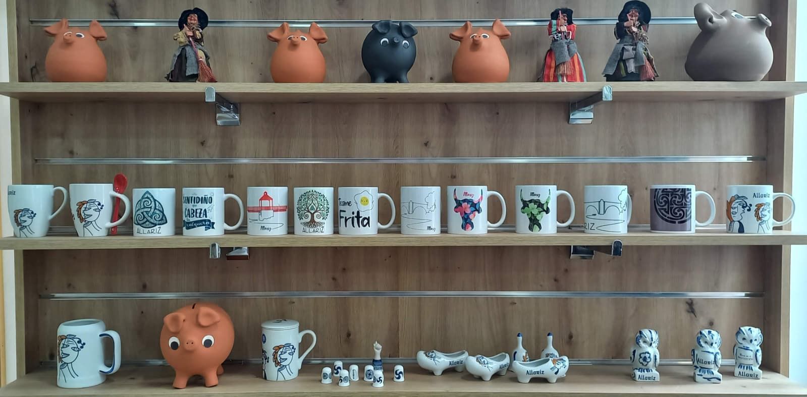 Estanterías de madera que exponen tazas y figuras, con una colección con temática de cerdo.