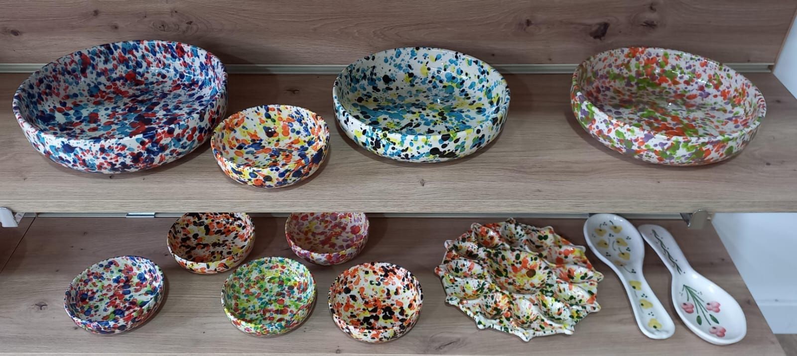 Cuencos y cucharas moteados de colores en estantes de madera.