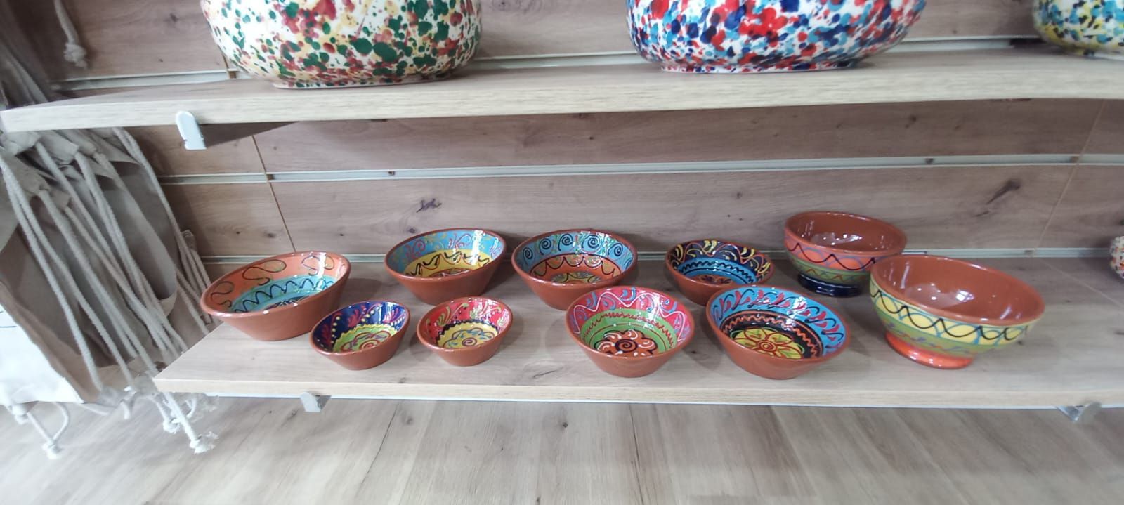Cuencos con diseños interiores coloridos dispuestos en estantes de madera.