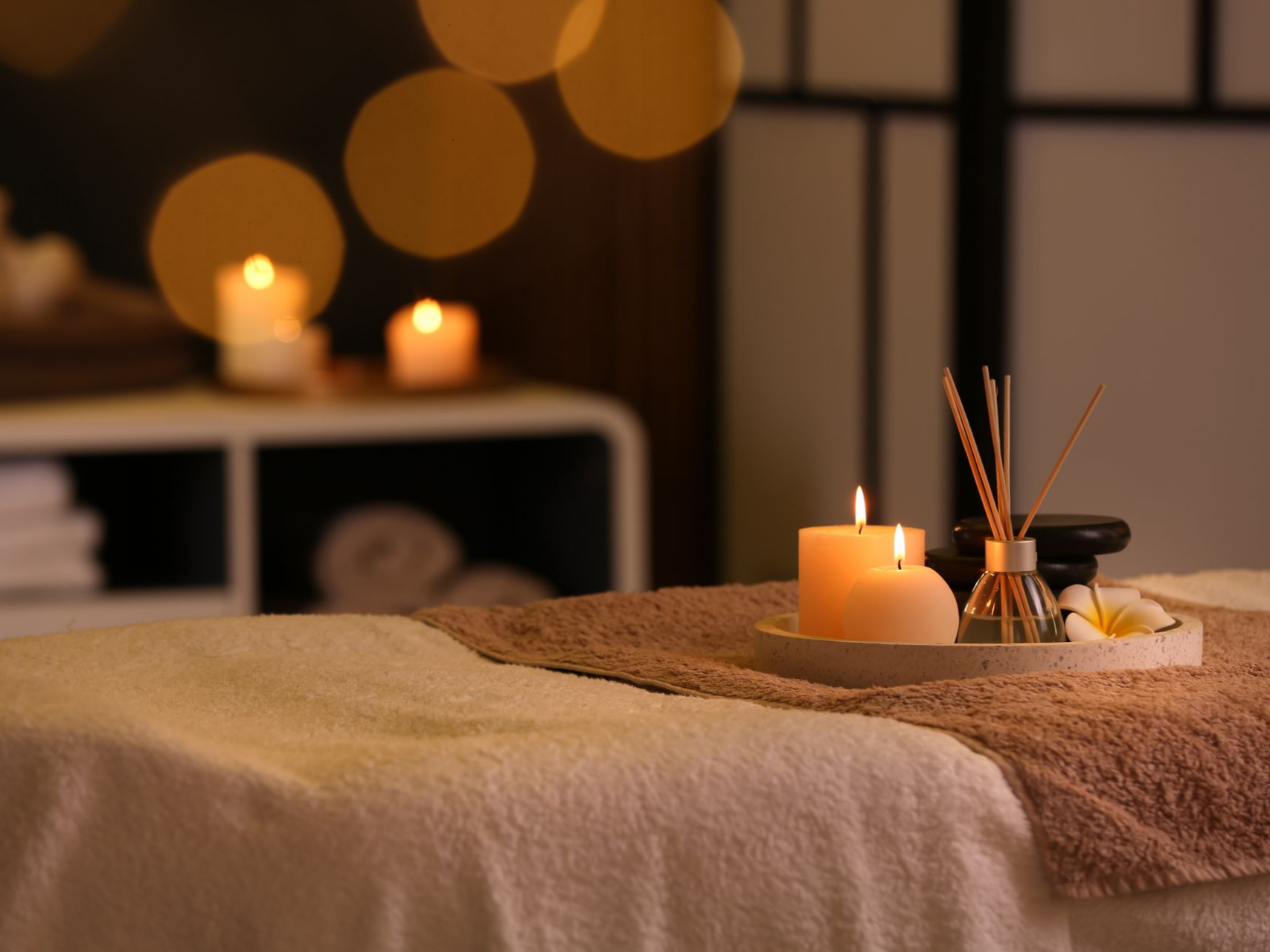 Table de massage avec bougies et aromathérapie dans un spa à l'éclairage tamisé.
