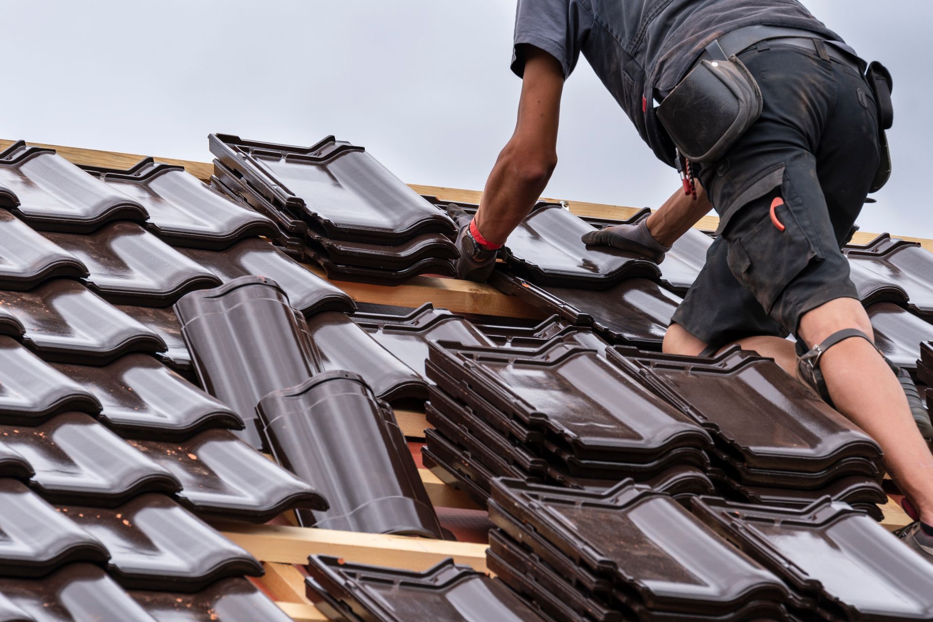 Professionnel sur une toiture en train de poser des tuiles noires