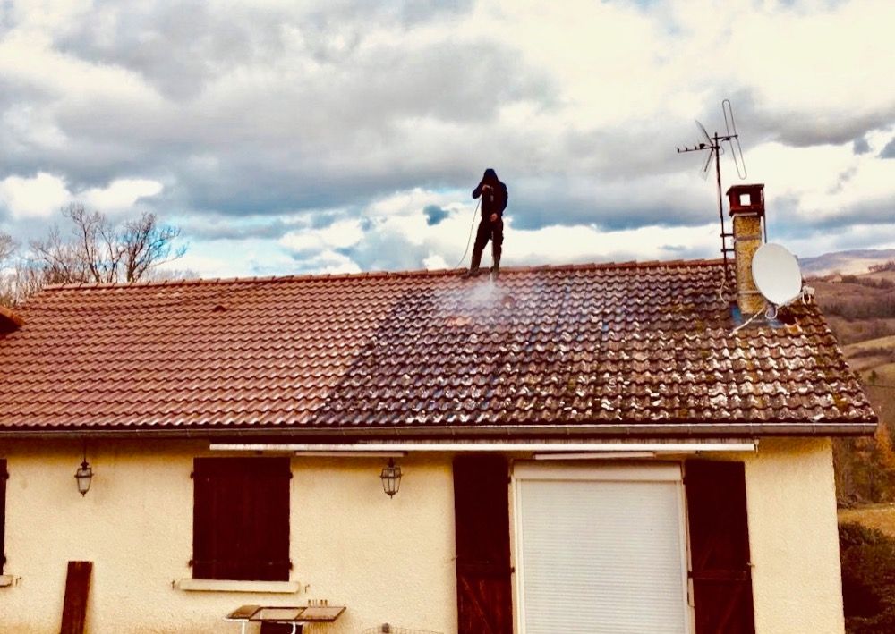 Professionnel debout sur un toit le nettoyant avec un jet haute pression