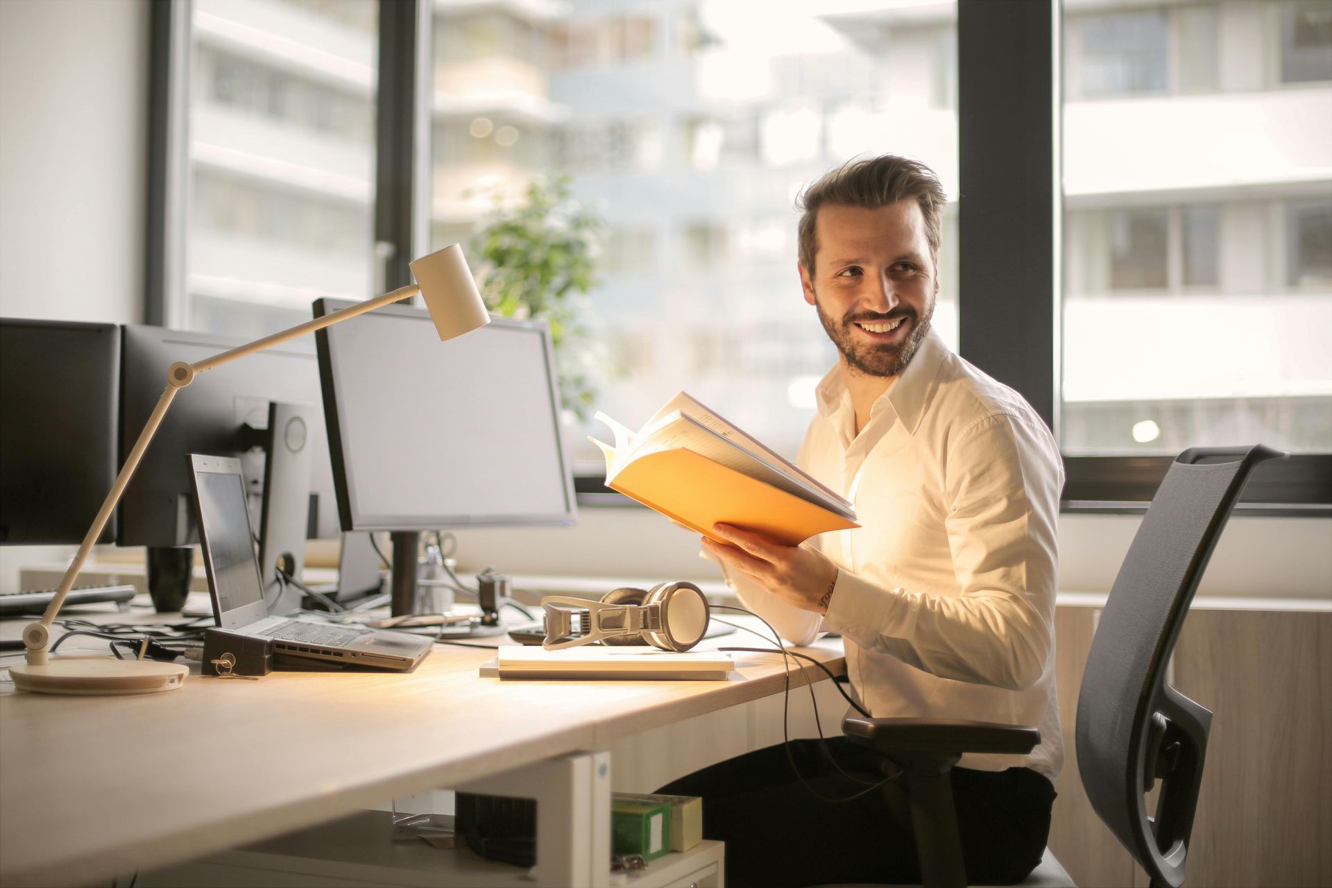 Un uomo è seduto alla scrivania di un ufficio e tiene in mano una cartella.