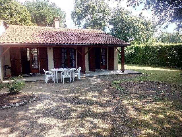 Terrasse avec une table de jardin et des chaises en plastique 