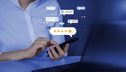 Une personne consulte son smartphone, avec interface d’avis en ligne affichant des commentaires clients et des notes.