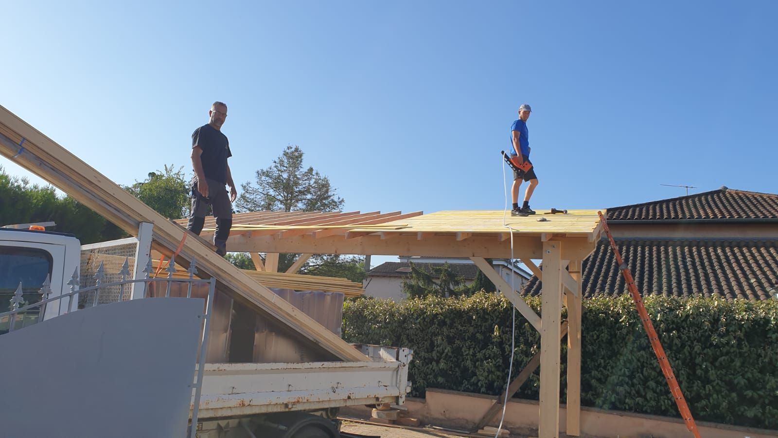 Intérieur d'un grenier en construction, avec charpente apparente et fenêtres baignées de soleil.