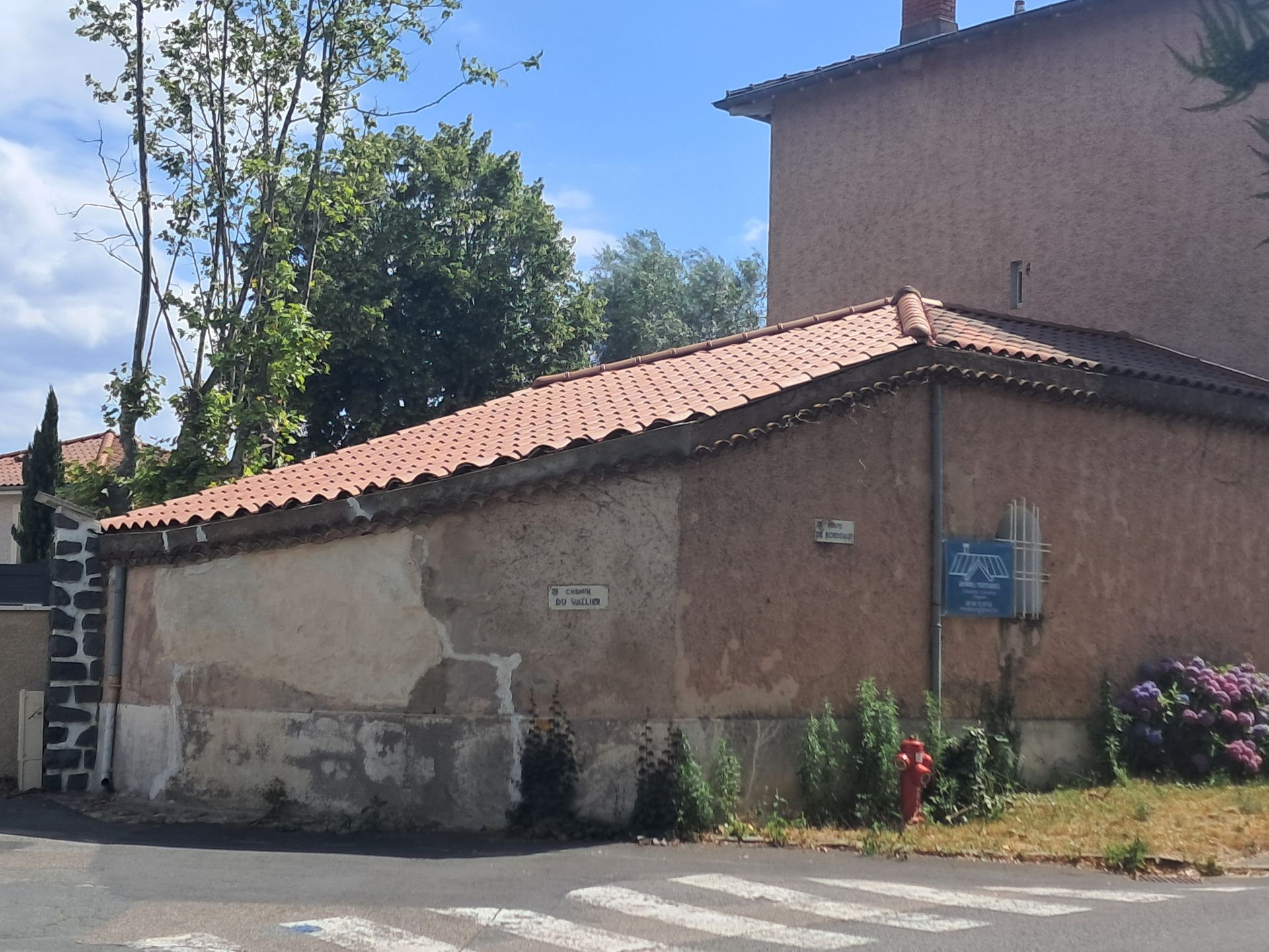 Couverture en tuiles gris foncé avec deux cheminées en briques et des fenêtres de toit.