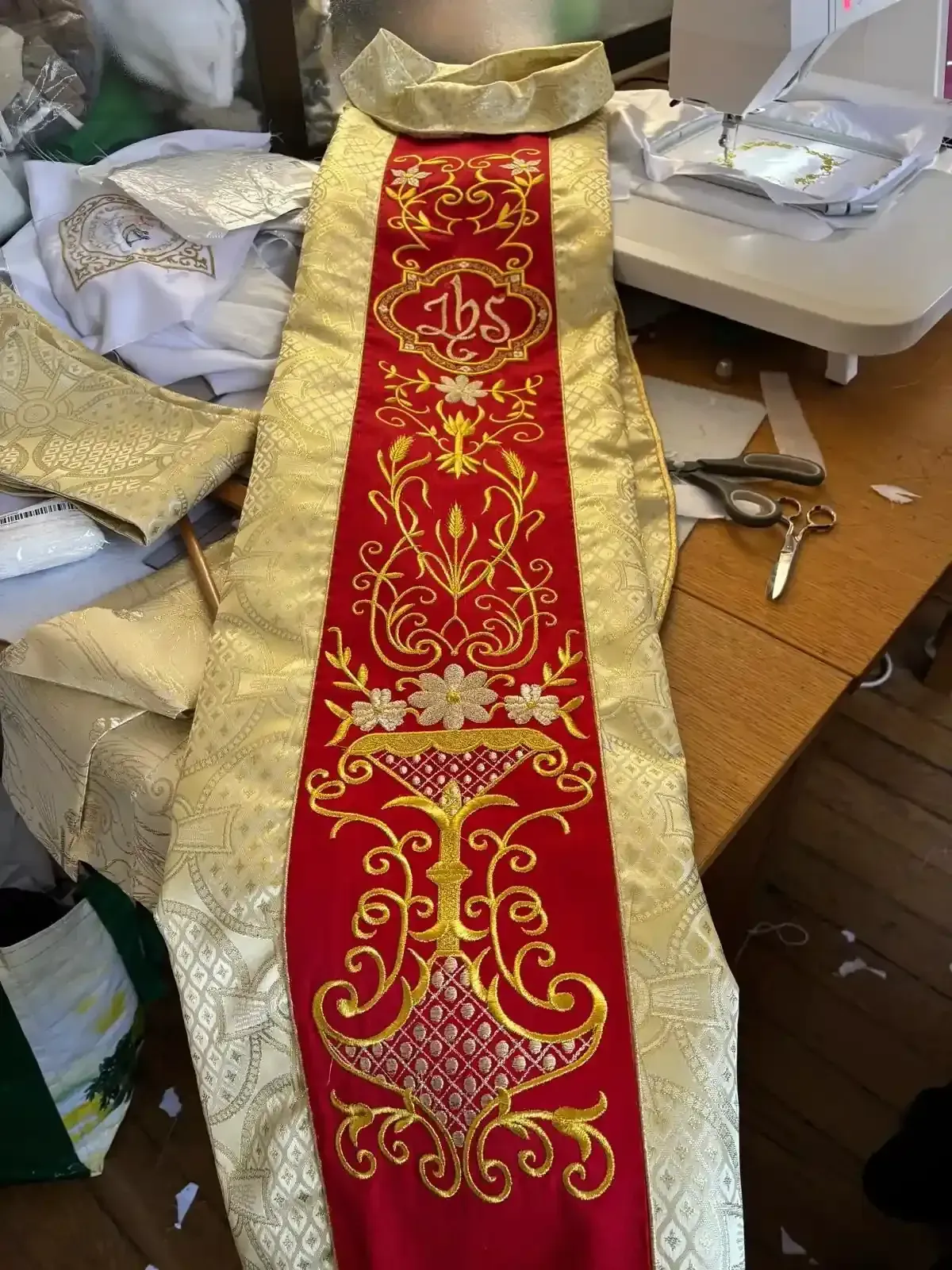 Estola litúrgica roja y dorada con símbolos religiosos bordados.