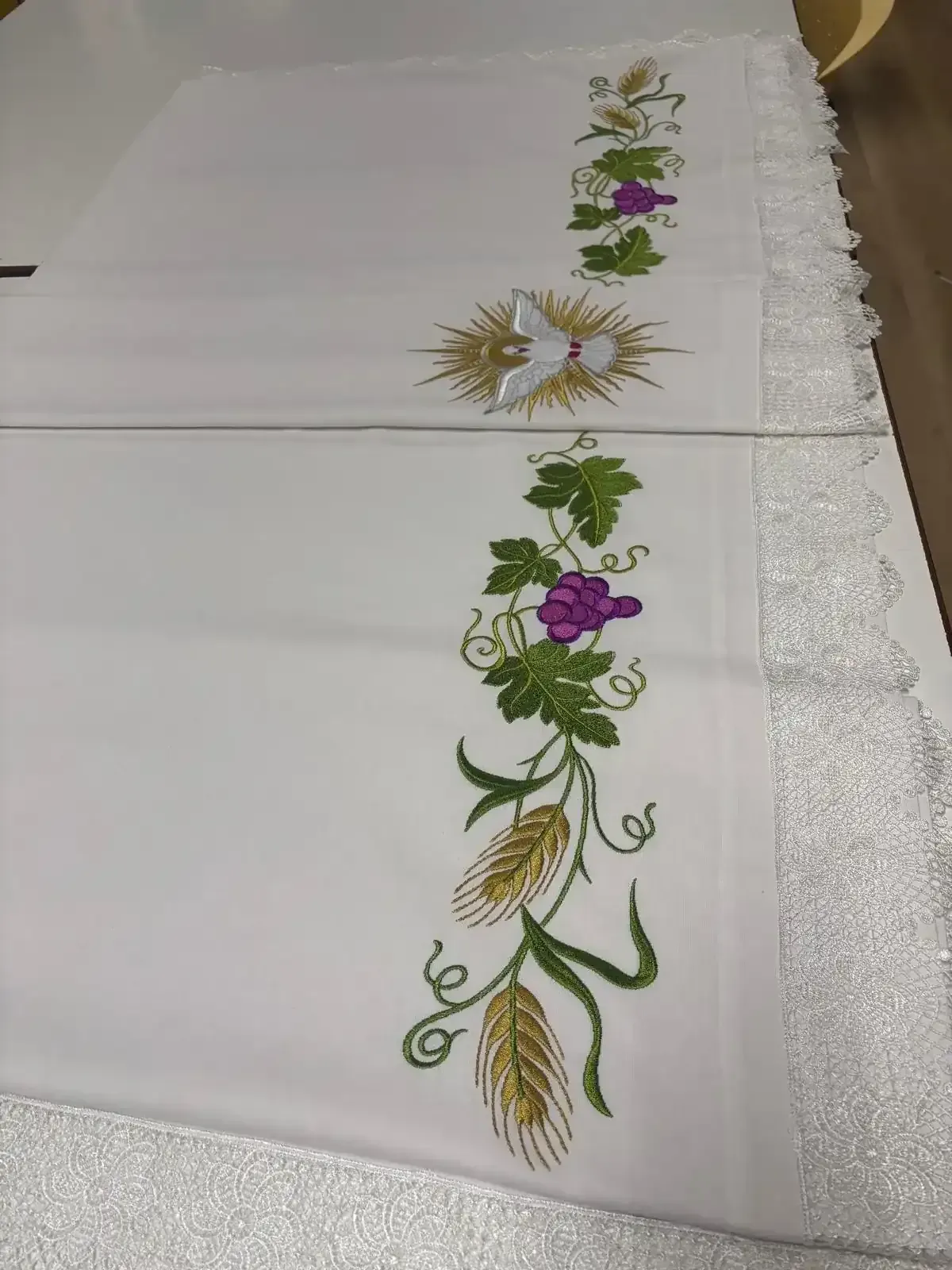 Tela blanca con diseños florales bordados, una paloma y trigo.