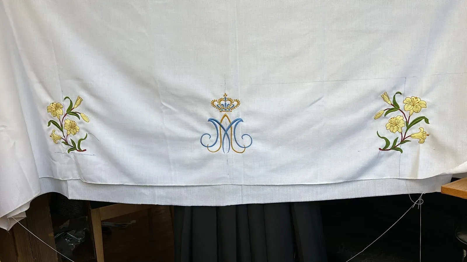 Lino blanco con diseño floral bordado y monograma debajo de la corona.