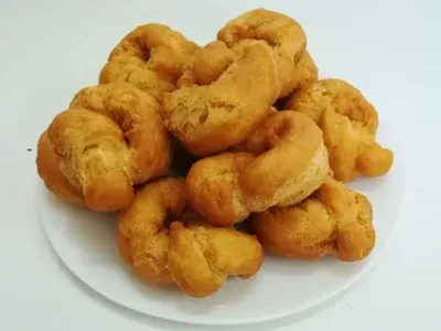 Pila de pasteles de masa fritos de color dorado sobre un plato blanco.