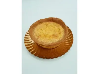 Tarta de crema pastelera sobre un plato decorativo festoneado de color dorado, sobre un fondo claro.