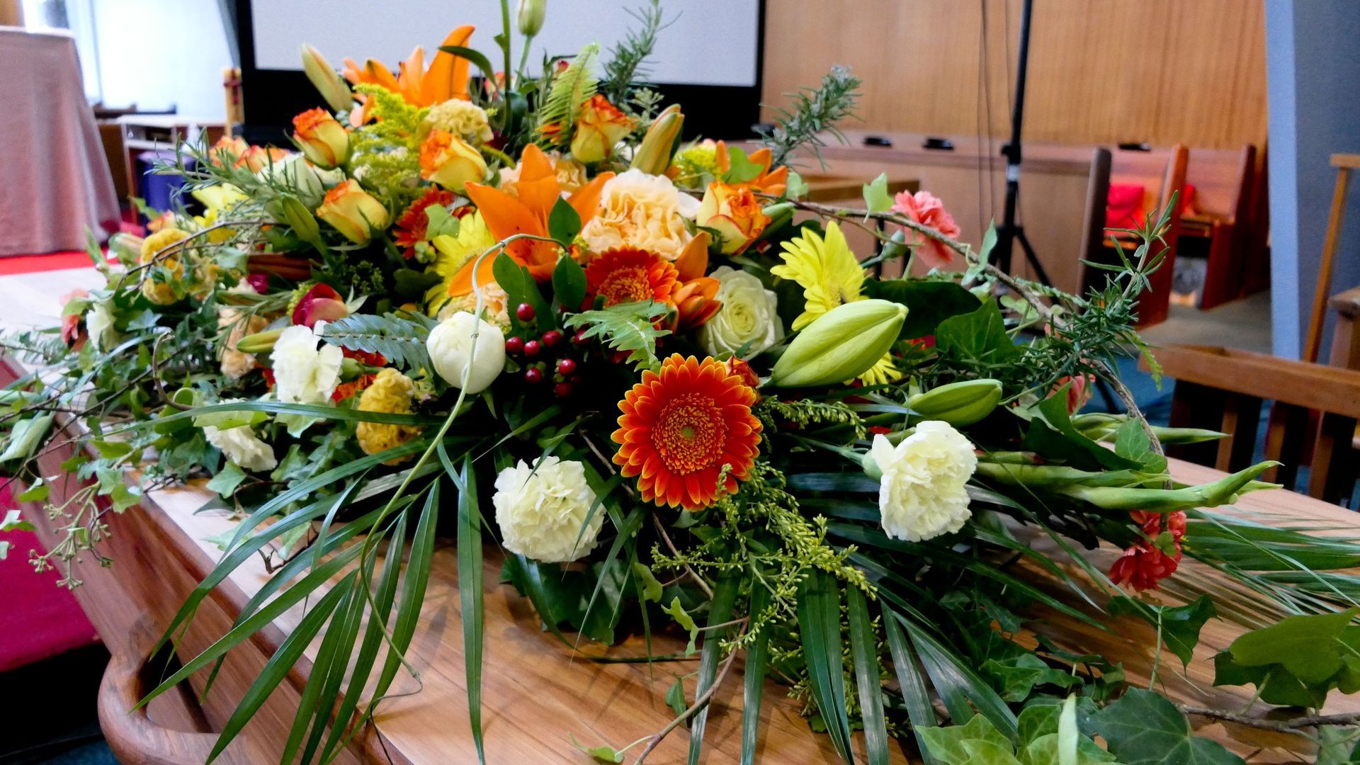 Un ataúd está decorado con flores y hojas para un funeral.