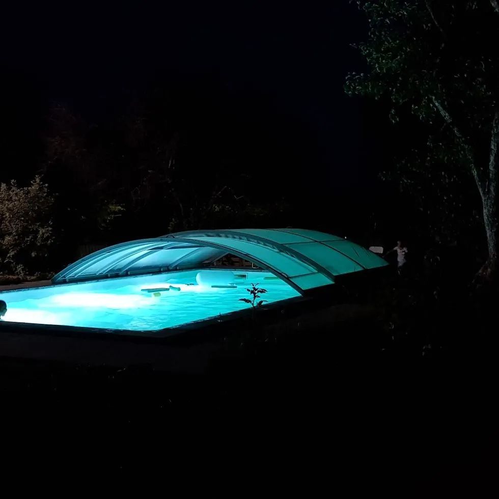 Piscine éclairée la nuit avec le volet de protection