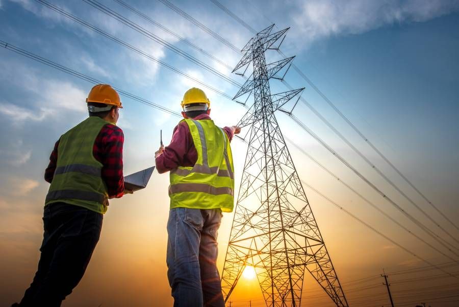 Ein Elektriker der auf einen Strohmmast zeigt