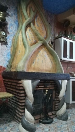 Chimenea elaborada con diseño retorcido en forma de árbol, base de ladrillo y columnas decorativas en un entorno de cocina.