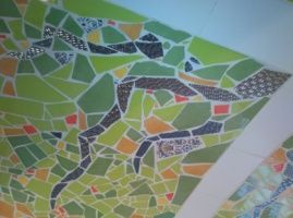 Arte de mosaico con formas verdes, naranjas y negras que forman una figura sobre un fondo verde.