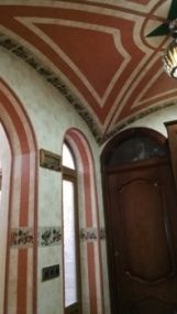 Interior con puertas arqueadas ornamentadas, paredes con rayas rosas y blancas y un techo decorado.